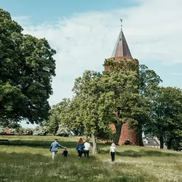 A family walking up to Danmarks Borgcenter in Zealand, Denmark. Surrounded by greenery.
