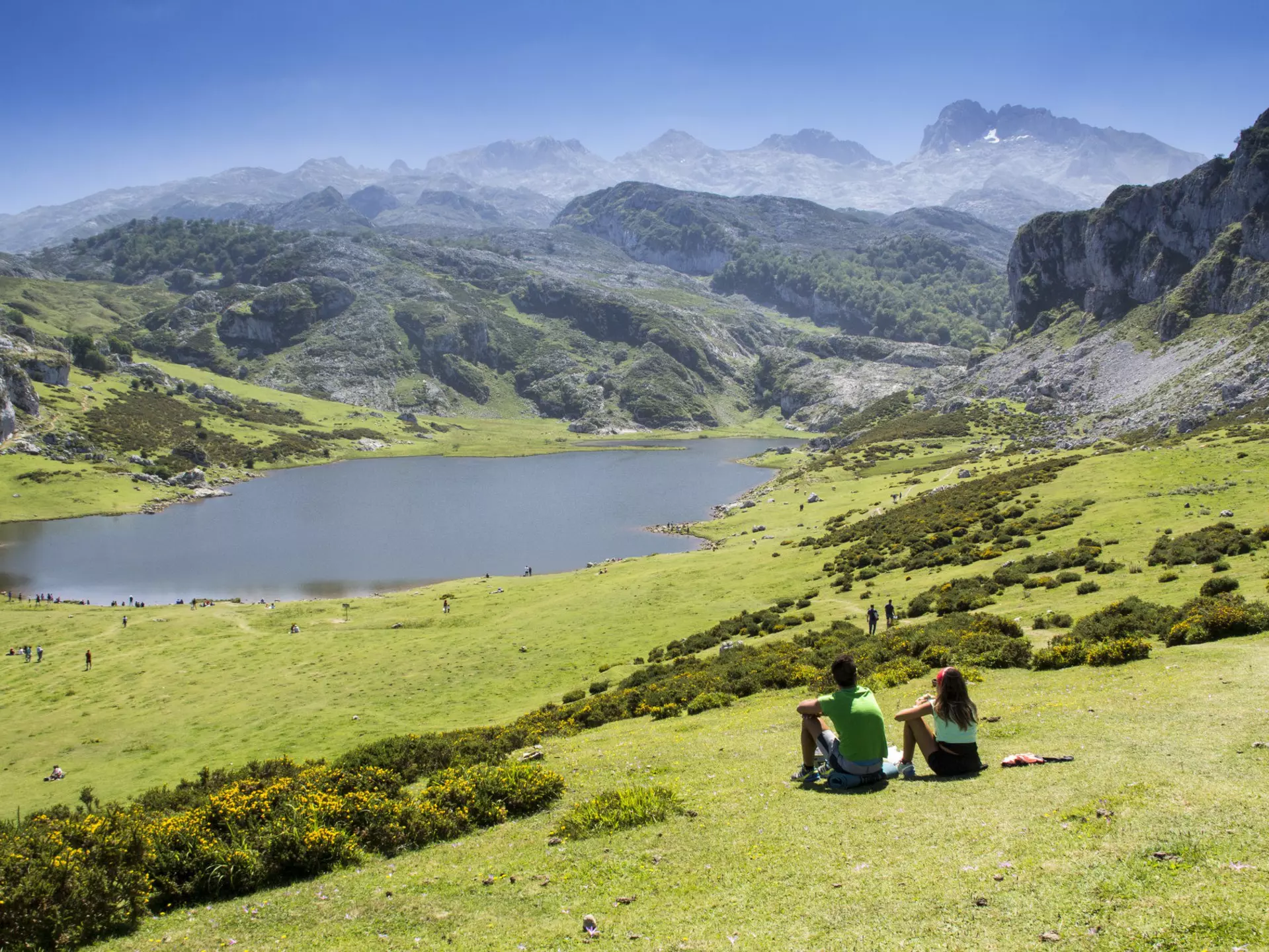 Young couple sitting on the grass overlooking the lakes in a mountainous region