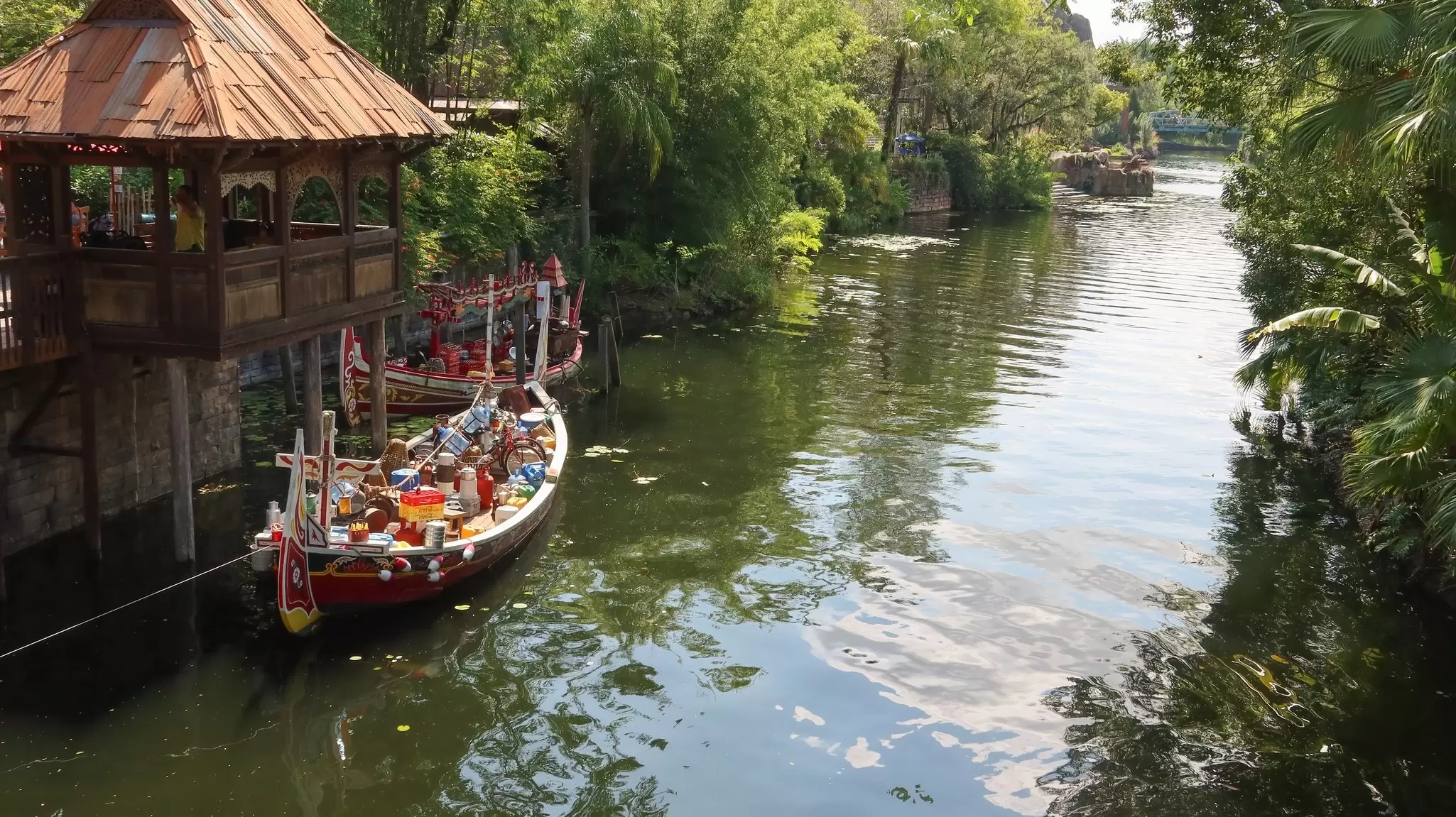 Small wooden boats docked on a river surrounded in dense foliage at Disney's Animal Kingdom, Orlando, Florida. 