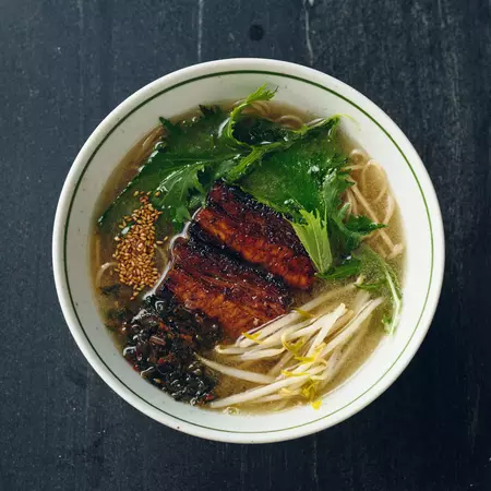 Soup with noodles, meat and vegetables in a bowl on a black table