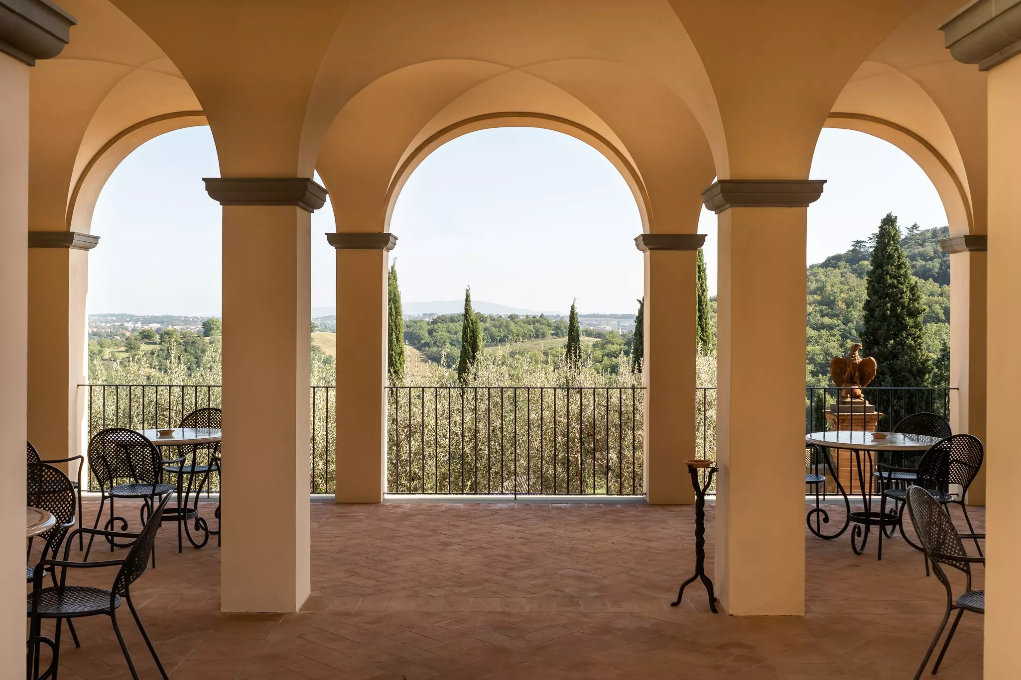 A covered porch with tables and chairs and Umbria's hills in the background