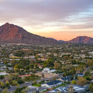 Sunset over Camelback Mountain, with a view of houses and trees in the foreground