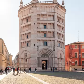 A view of the baptistery of Parma in Duomo square (Piazza Duomo) while tourists walk nearby.