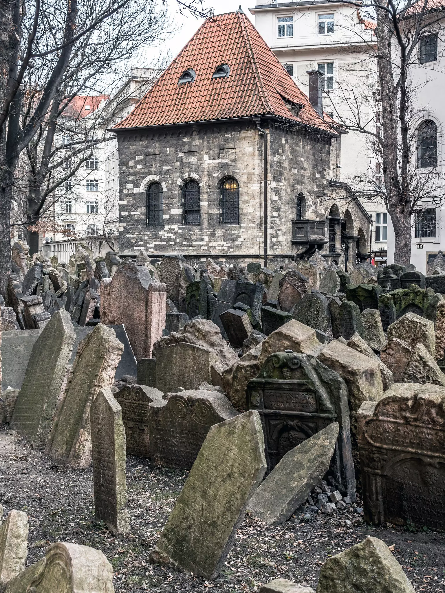 A series of old gravestones packed tightly together and in various conditions in a cramped cemetery space.
