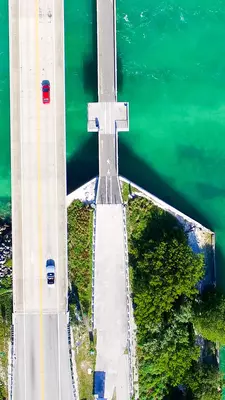 Aerial view of a four lane highway bridge that is crossing a green ocean