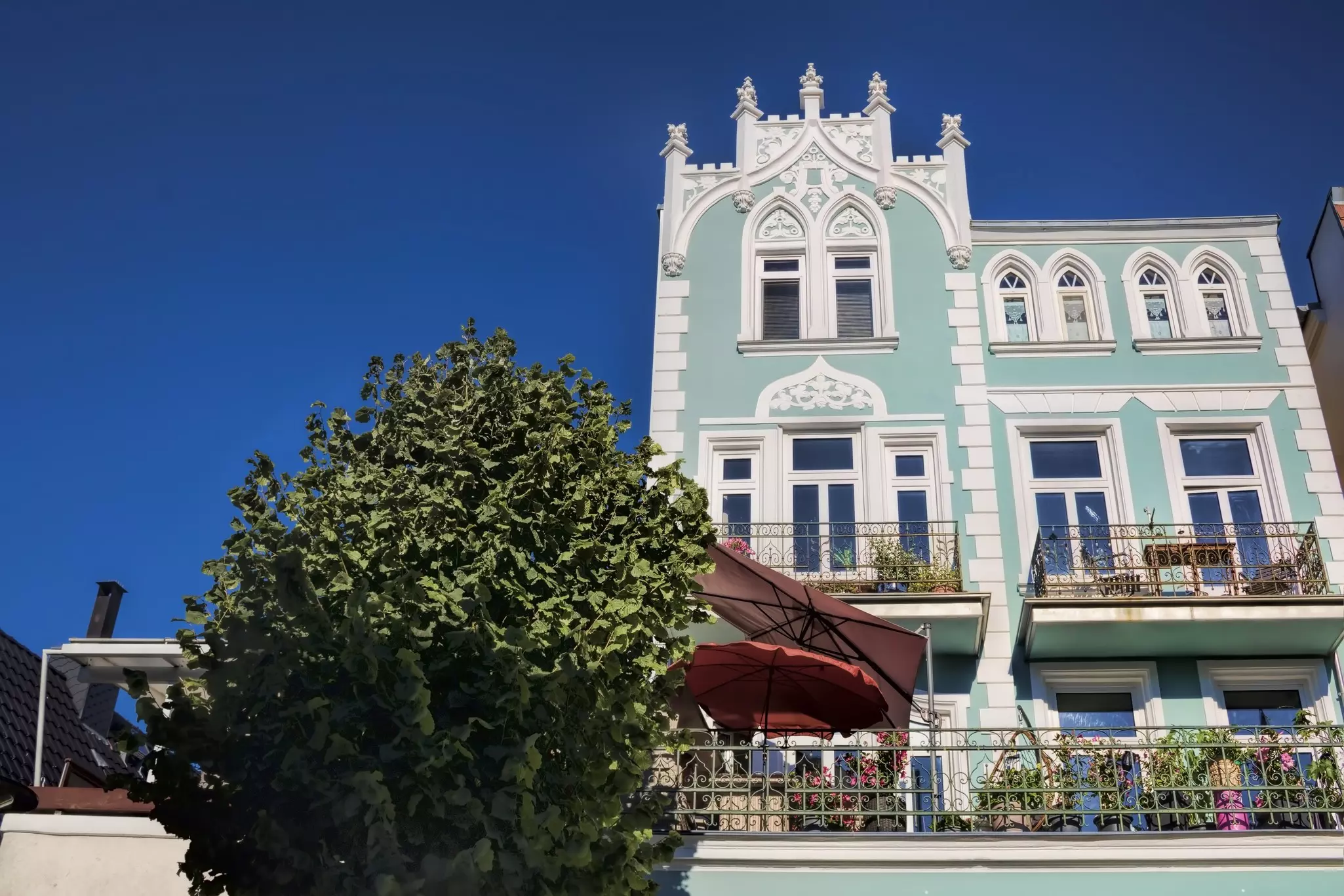 A light green villa with ornate windows on a sunny day.