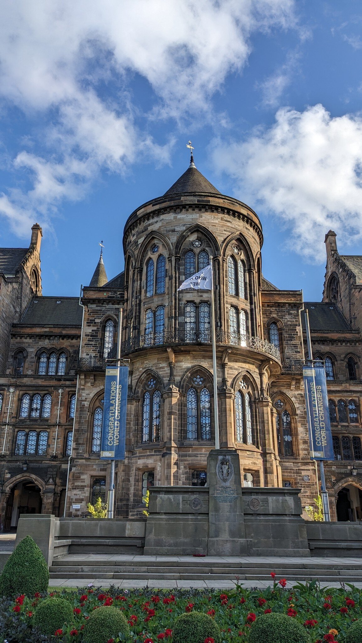 Exterior view of the Hunterian Art Gallery in Glasgow, showcasing its stunning architecture and beautifully landscaped gardens against a vibrant blue sky.