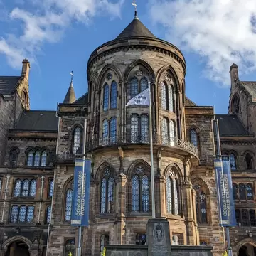 Exterior view of the Hunterian Art Gallery in Glasgow, showcasing its stunning architecture and beautifully landscaped gardens against a vibrant blue sky.