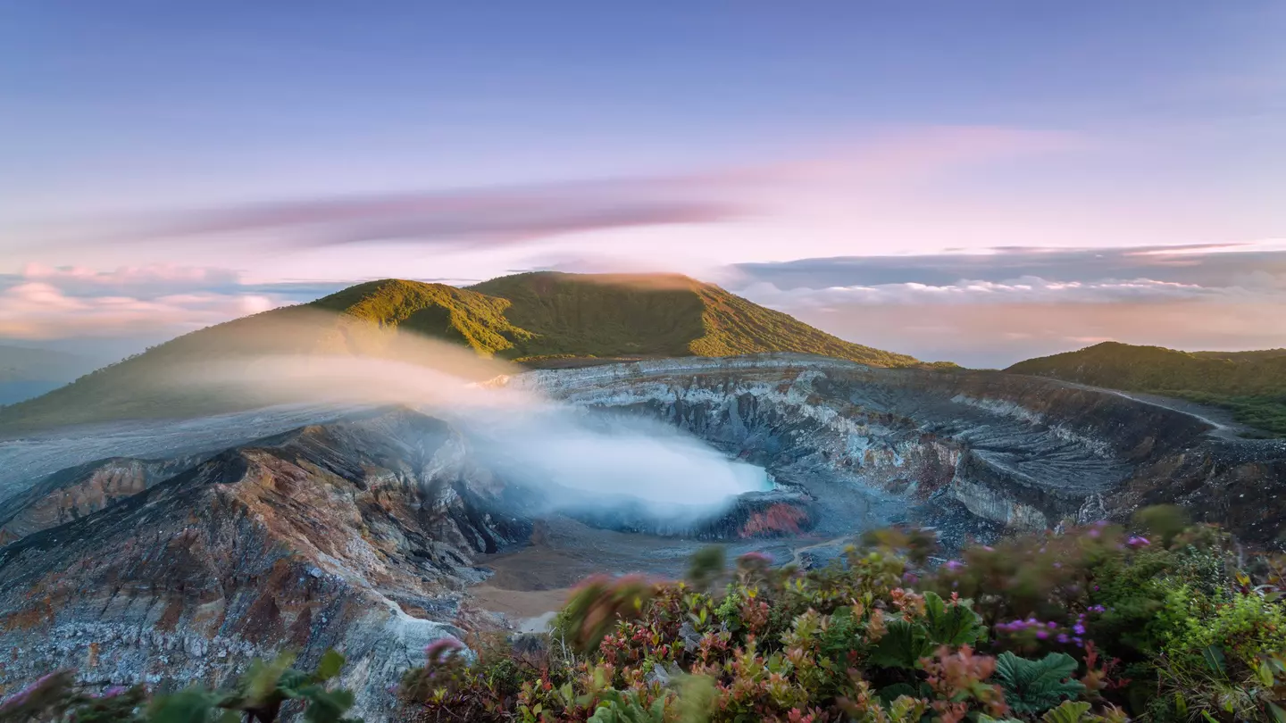 High angle view of crater emitting smoke at sunset
