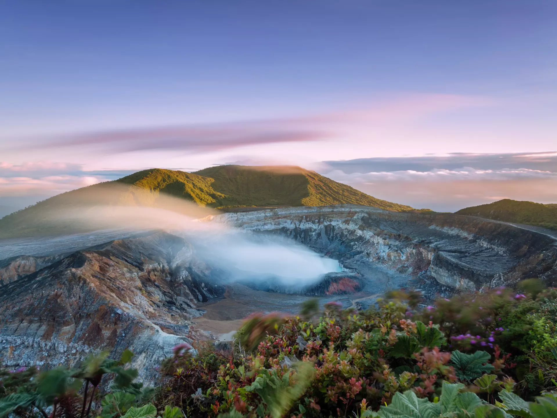 High angle view of crater emitting smoke at sunset