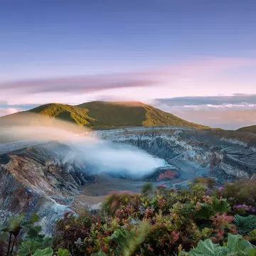 High angle view of crater emitting smoke at sunset
