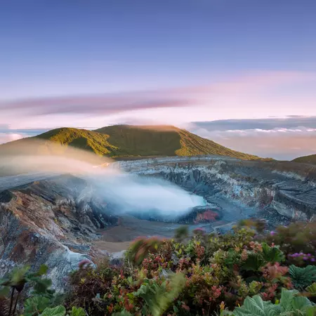 High angle view of crater emitting smoke at sunset