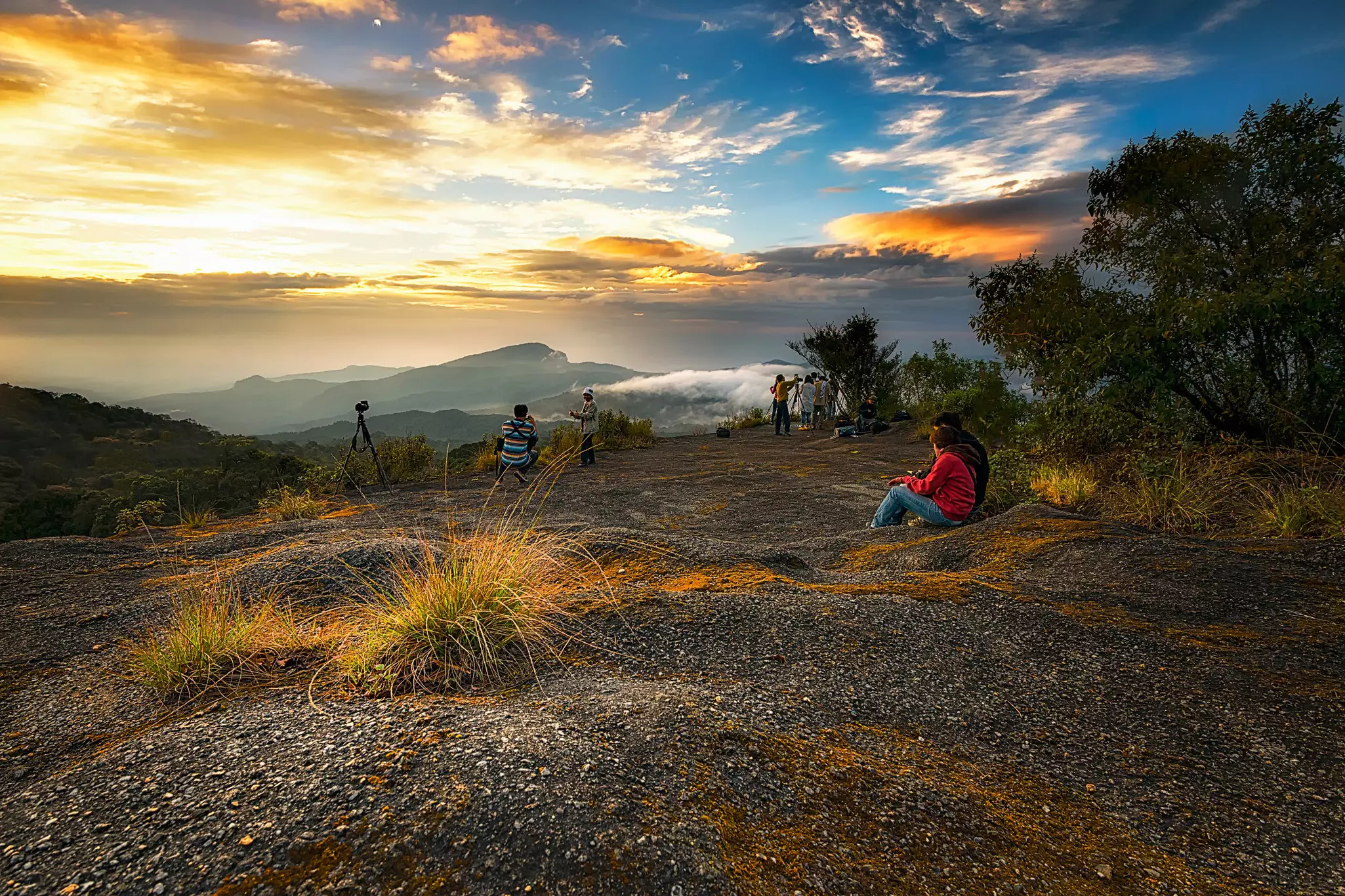 Groups of people watch the sunrise from a mountain viewpoint