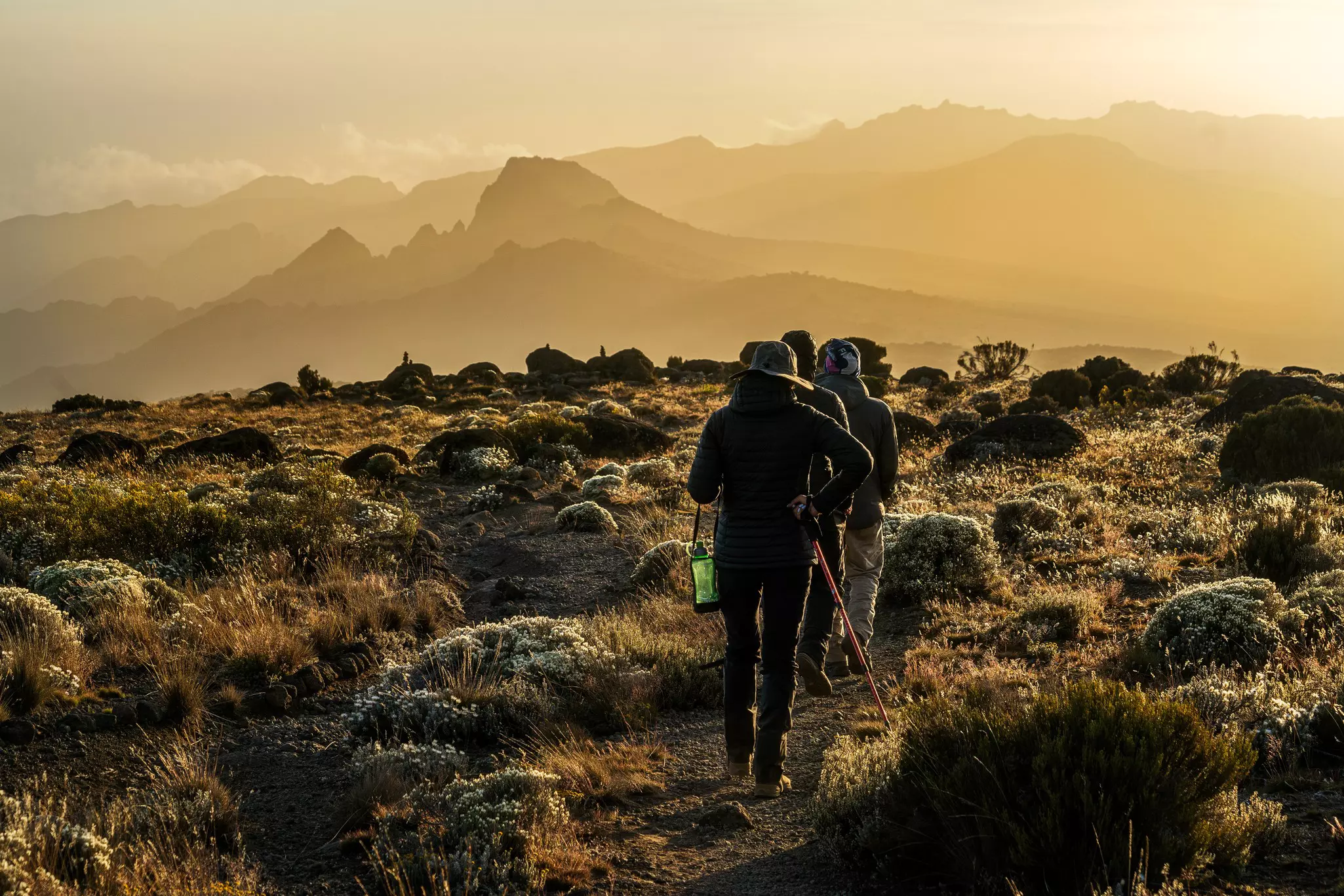 A group of people hike along a rocky ridge at sunset in Tanzania