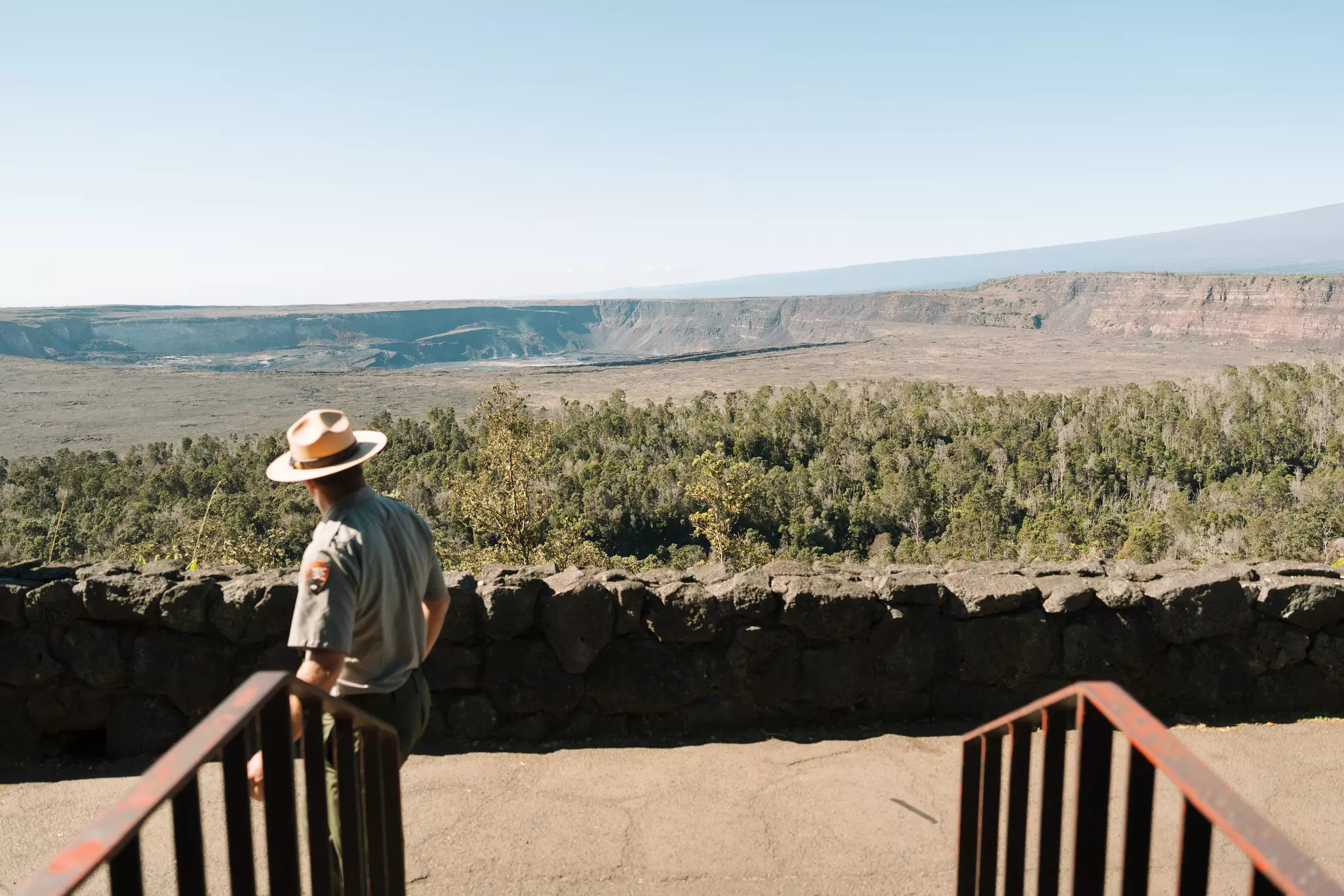 A park ranger looks out at a calder and low, flat hillside on an overcast day.