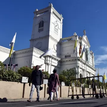Low-angle view of two people walking past St. Anthony’s Shrine in Kochchikade, Colombo, Sri Lanka.