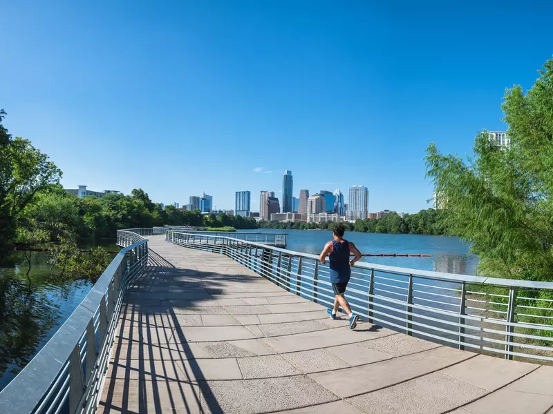 Panorama view Downtown Austin, Texas, US along Colorado River at daytime with cloud blue sky. View from Ann and Roy Butler Hike-and-Bike Trail and boardwalk at Lady Bird Lake, unidentified man running  License Type: media  Download Time: 2023-04-05T16:22:23.000Z  User: fabricencoredesign31  Is Editorial: No  purchase_order:   