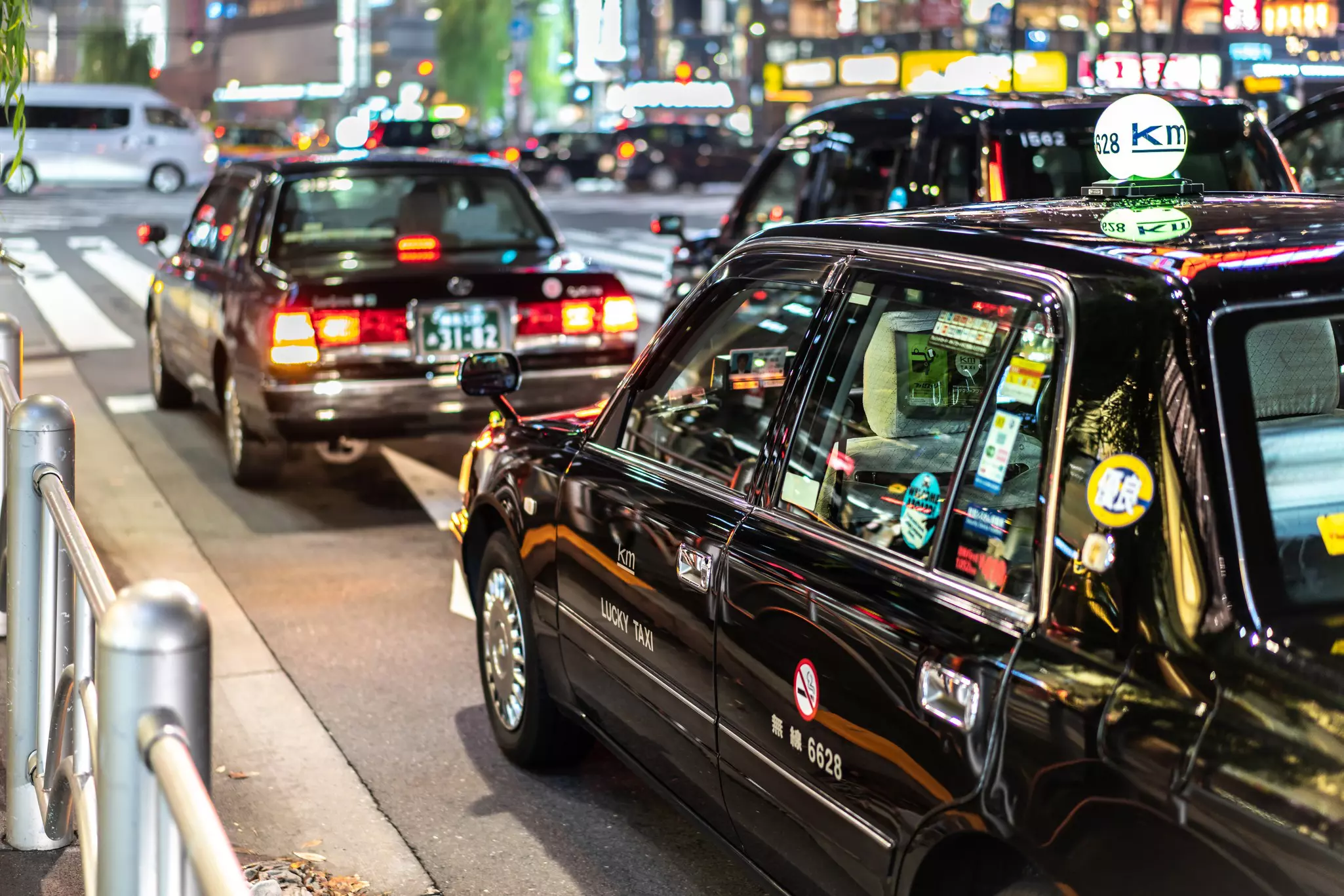 Black taxis are seen on a city street at night.