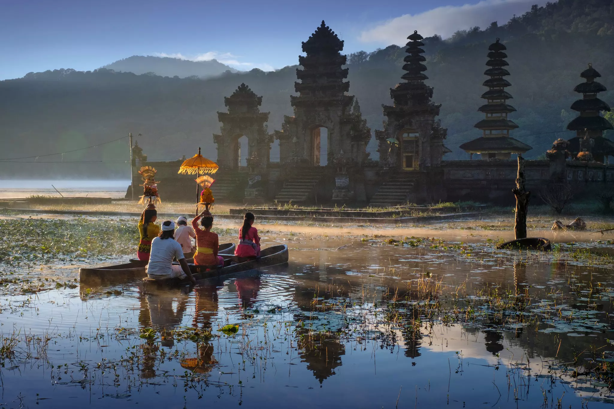 A Balinese family traveling by boat to reach Pura Ulun Danu Tamblingan temple for morning worship. 