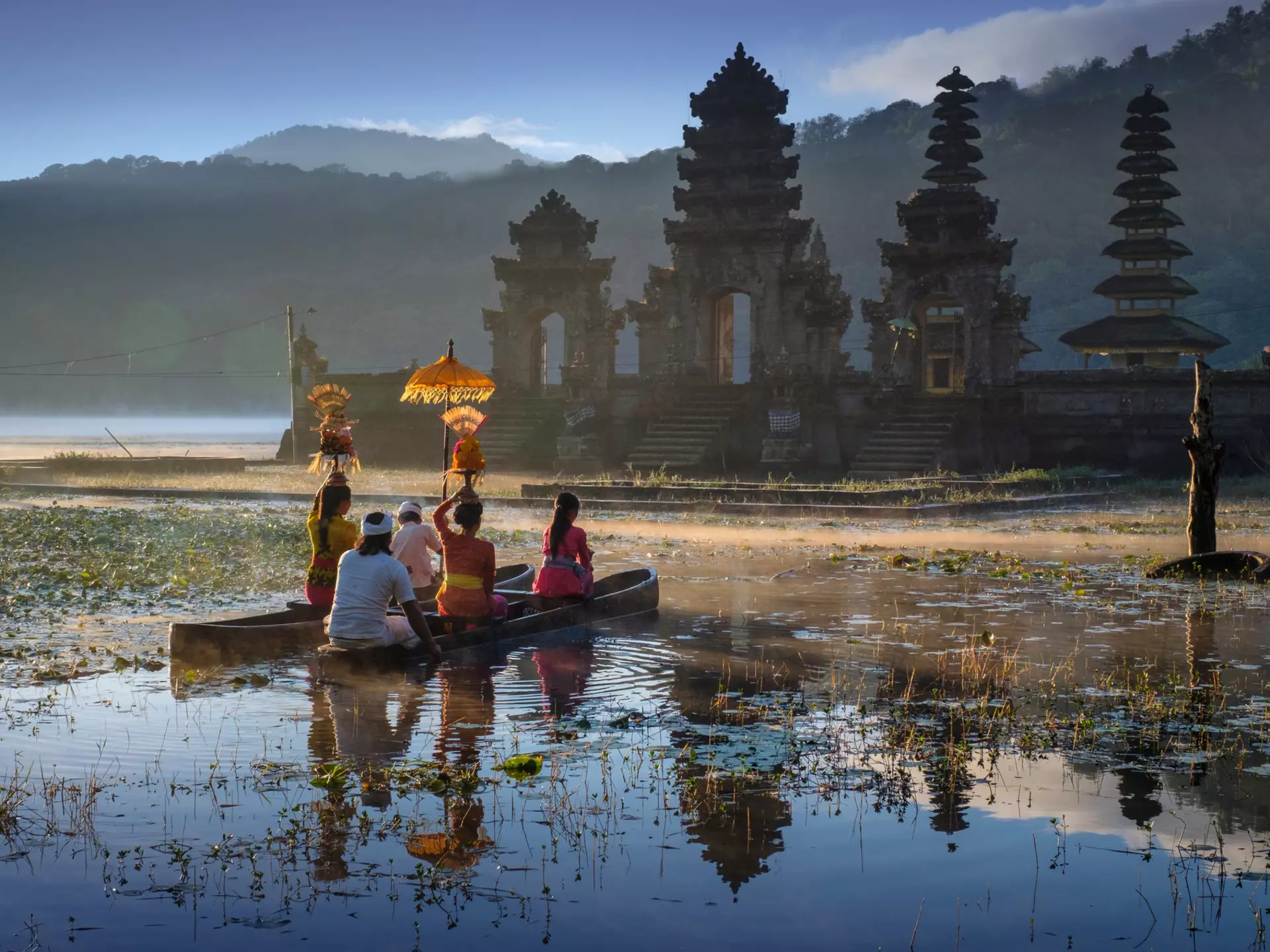 People traveling across water by boat to reach a temple in the morning. 