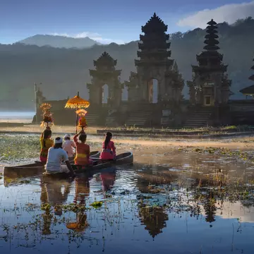 People traveling across water by boat to reach a temple in the morning. 