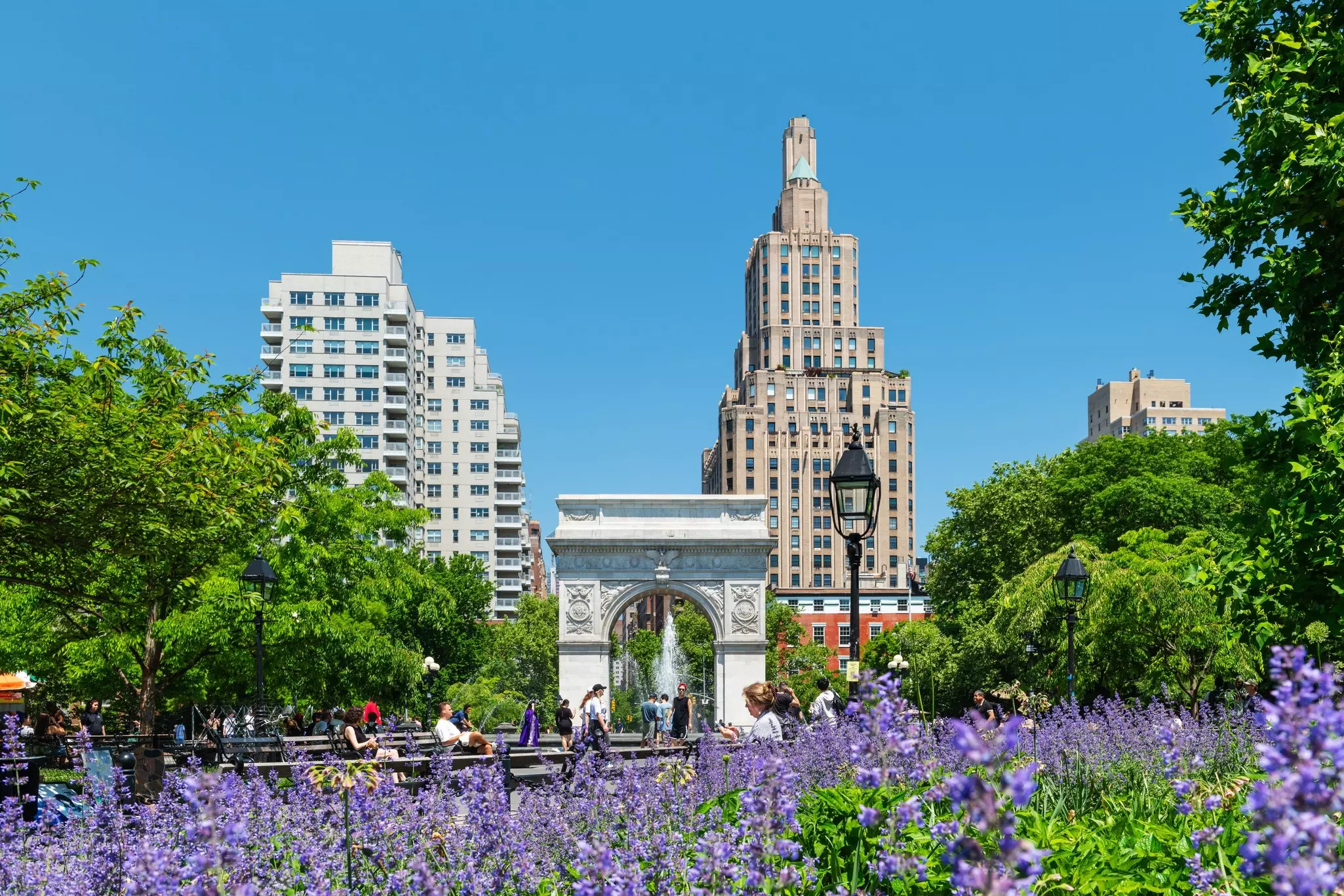 Washington Square Park in Manhattan with the iconic landmark arch and visitors enjoying a sunny spring morning.