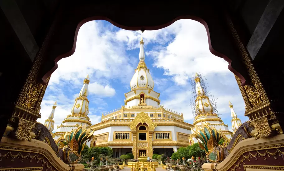 White and gold Phra Maha Chedi Chai Mongkol in Roi Et, northeastern Thailand, framed by a doorway with naga sculptures