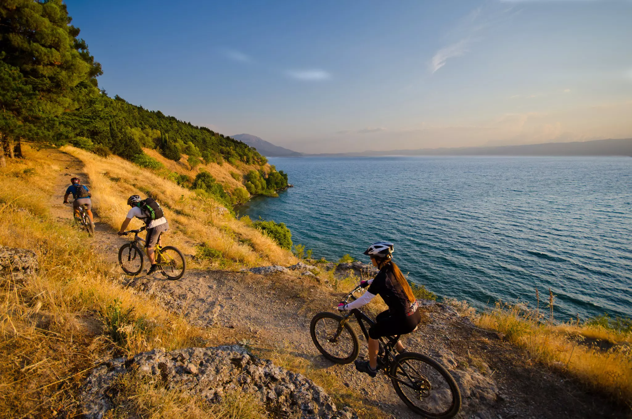 Three mountain bikers on a singletrack above lake Ohrid in Macedonia.