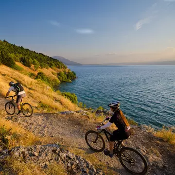 Three mountain bikers on a singletrack above lake Ohrid in Macedonia.