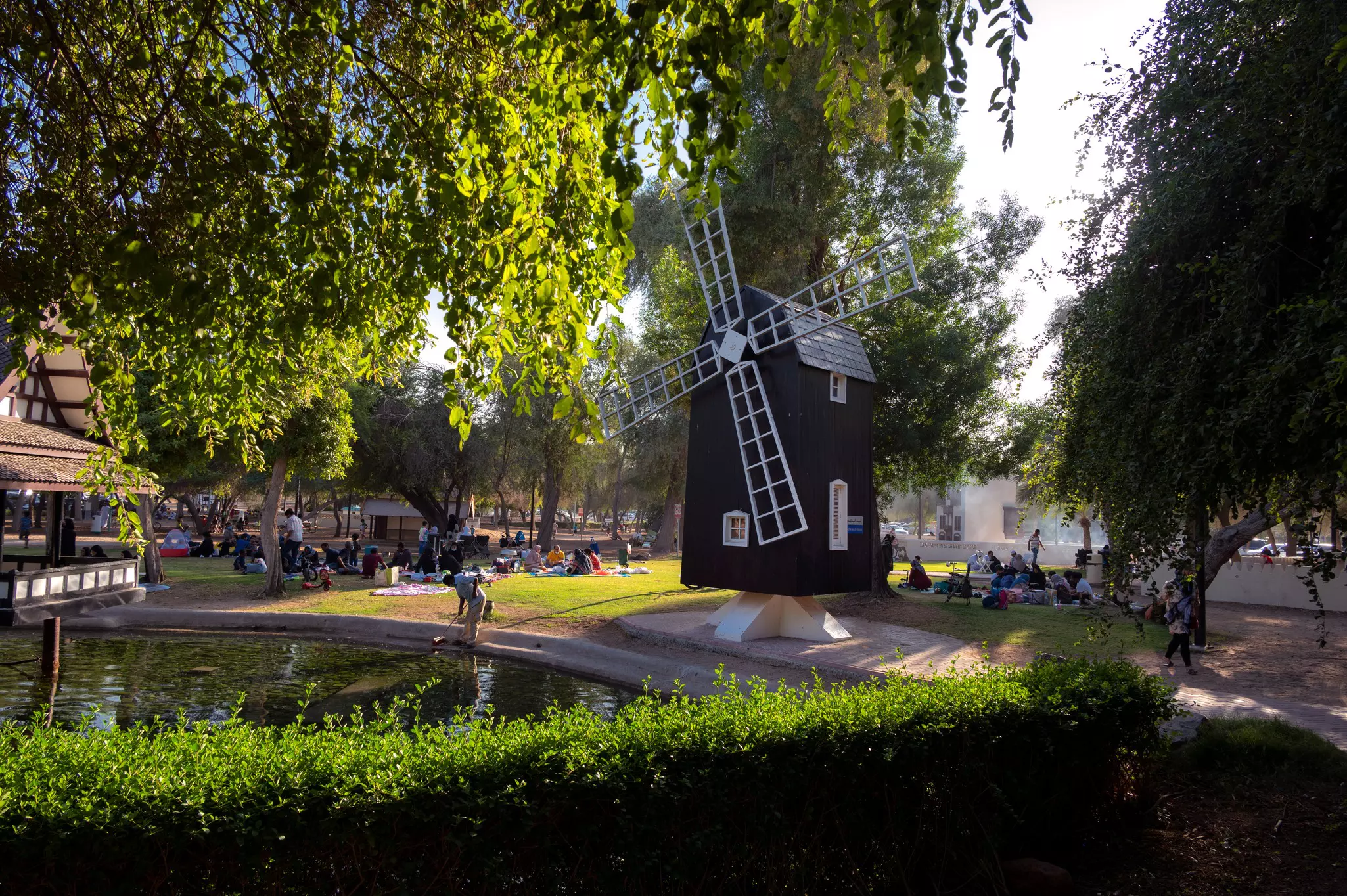 A beautiful model Dutch windmill  on display at the Mushrif park filled with families enjoying outdoors.,