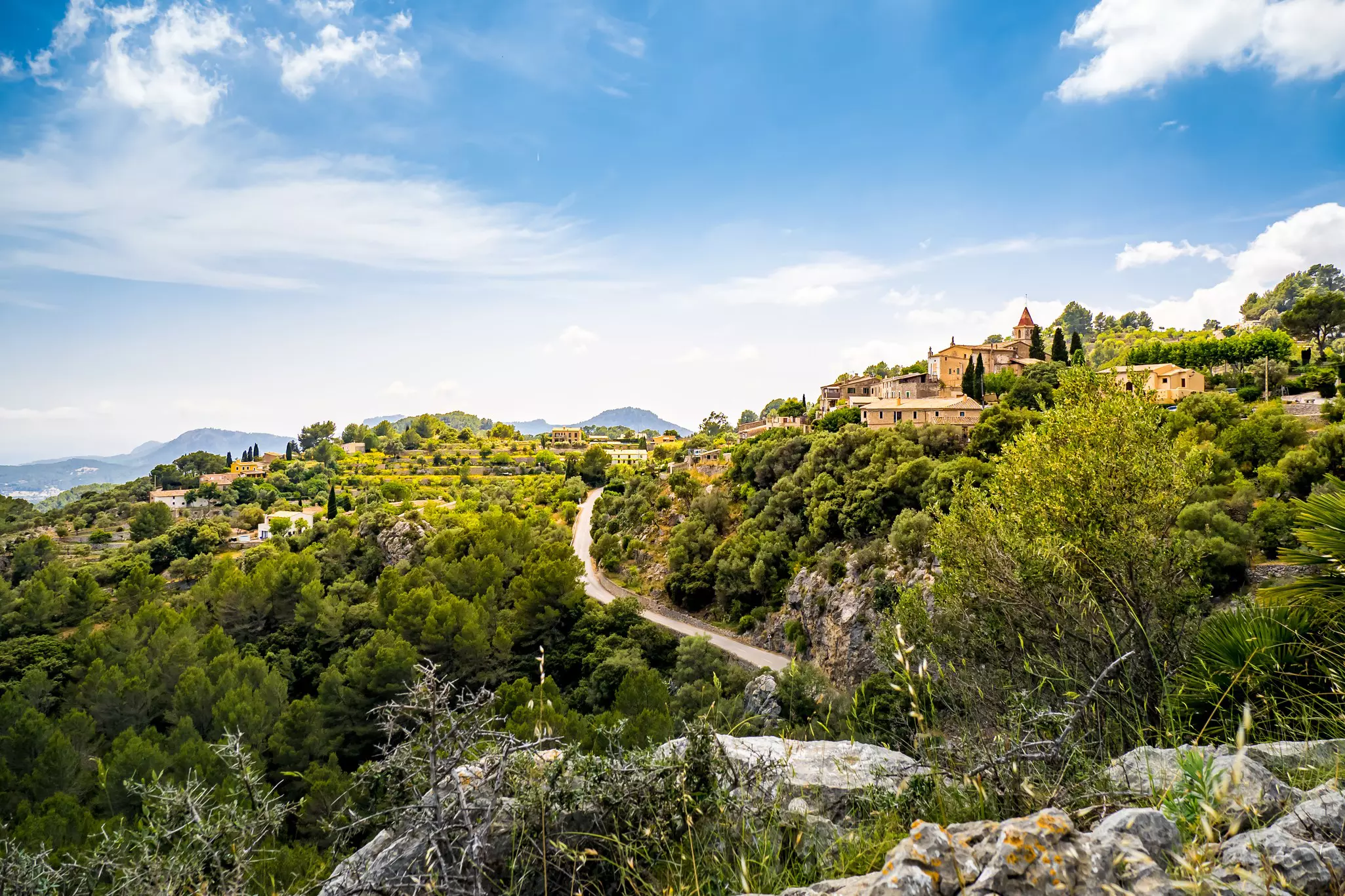 View from a boulder over the mountain village Galilea at Mallorca in the municipality of Puigpunyent surrounded by mountains, mediterranean forest and olive groves with view to the mediterranean sea.