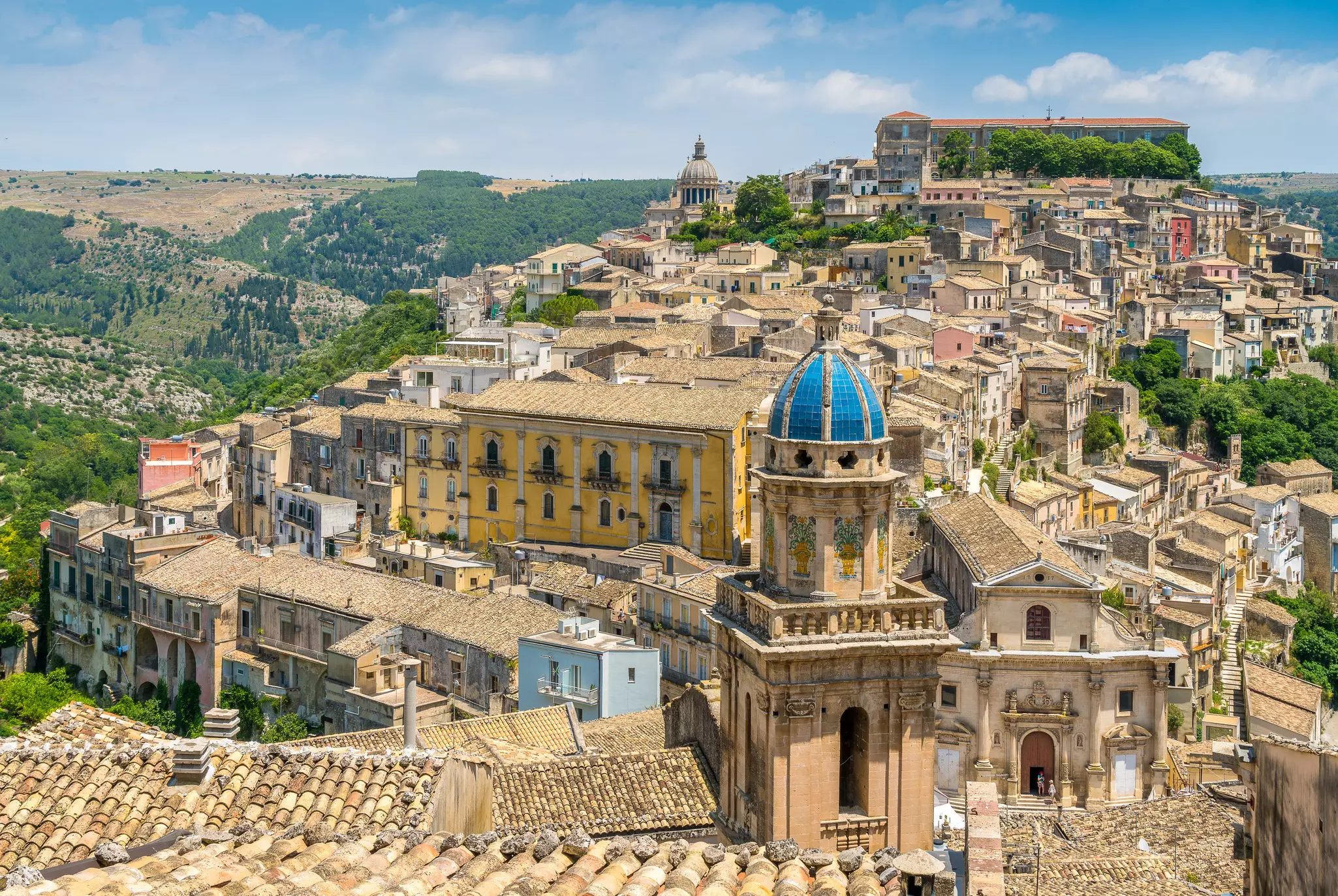 Aerial view of a hilly town with baroque architecture on a sunny day.