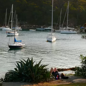 A woman relaxing near Forty Baskets Beach and boats in Sydney, Australia. 