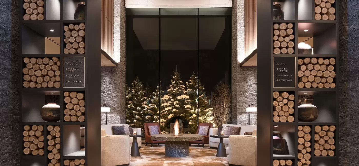 A hotel lobby in winter, with stacks of logs within the furniture: Higashiyama Niseko Village, a Ritz-Carlton Reserve, Japan