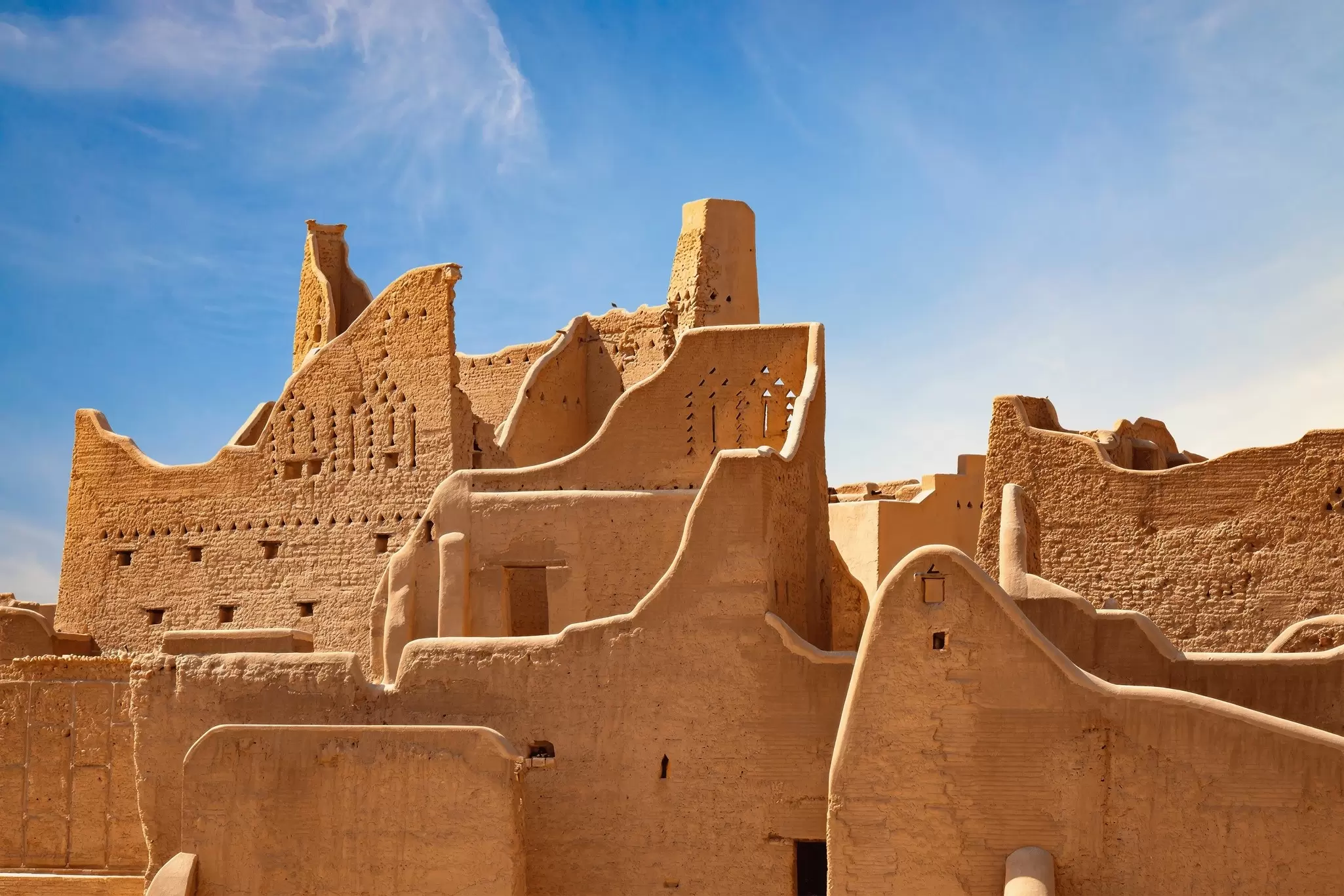 A historic city in golden stone under blue skies.