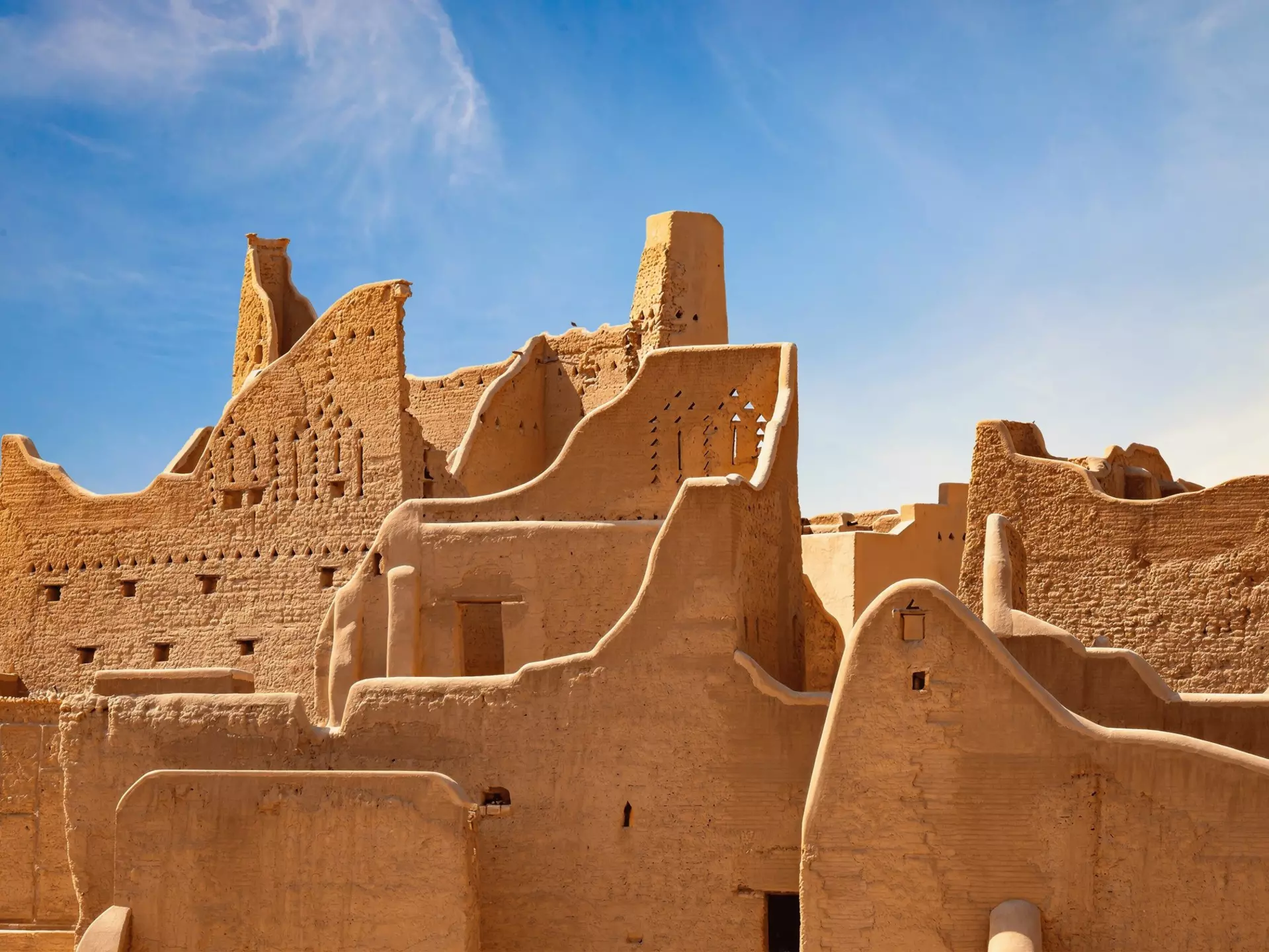 A historic city in golden stone under blue skies.