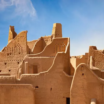 A historic city in golden stone under blue skies.