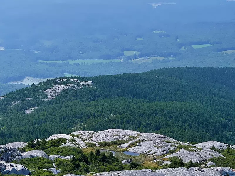 A sweeping view from the bare, rocky summit of Mount Monadnock, New Hampshire. The foreground is a fascinating landscape of large, rounded granite boulders and low-lying shrubs, while the background r, License Type: media, Download Time: 2026-04-10T17:16:23.000Z, User: Sarahstocking, Editorial: false, purchase_order: 65020 - Marketing or Sales - this includes sponsored articles, job: Digital , client: Summer in New Hampshire, other: Sarah Stocking