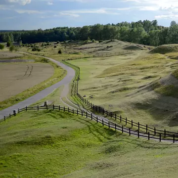 People wander up a steep mound in a rural area.