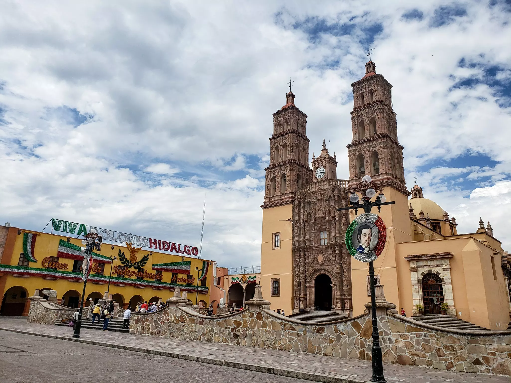 A small town square in front of a two-steepled church.