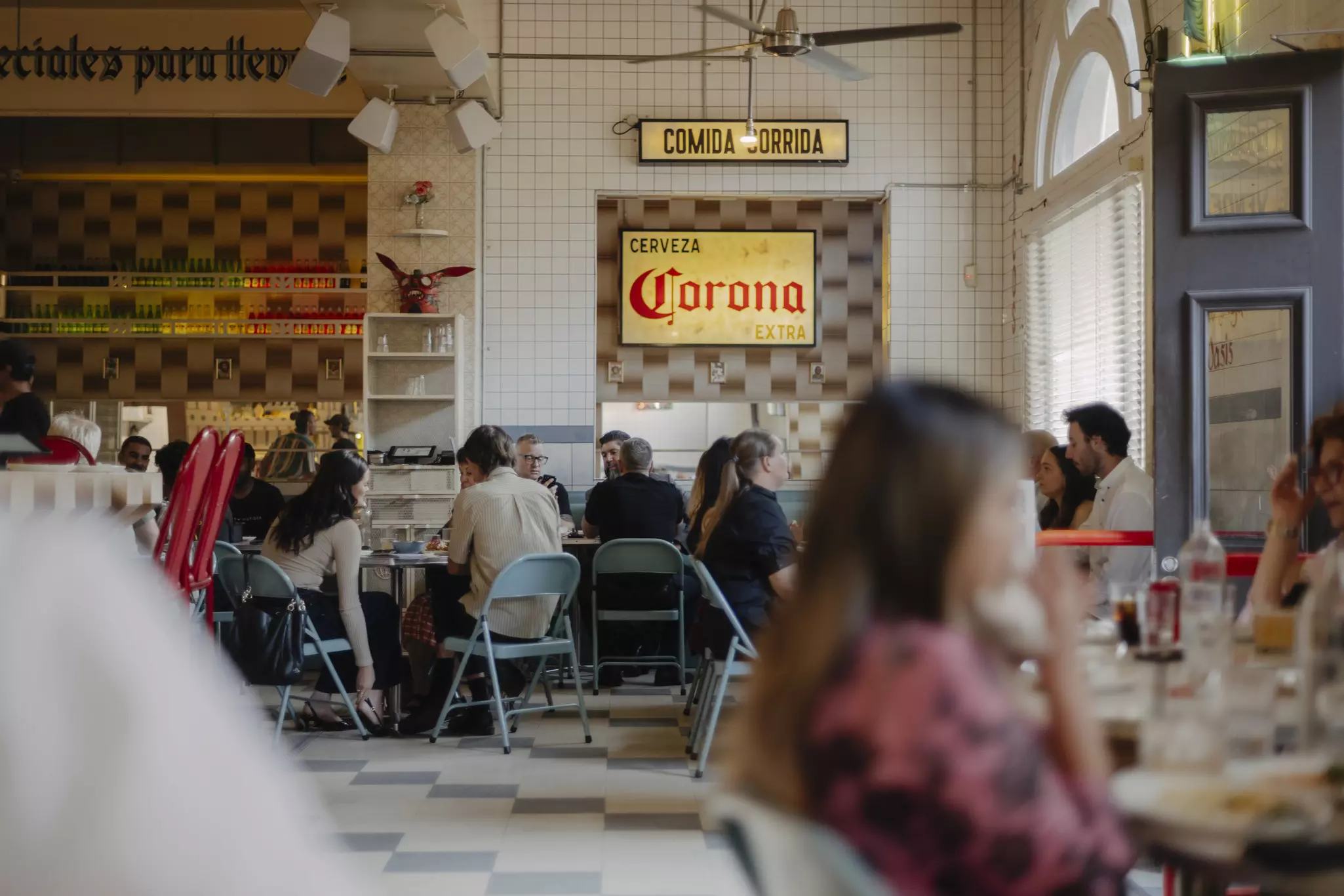People eat in a diner with signs written in Spanish on the tiled walls.