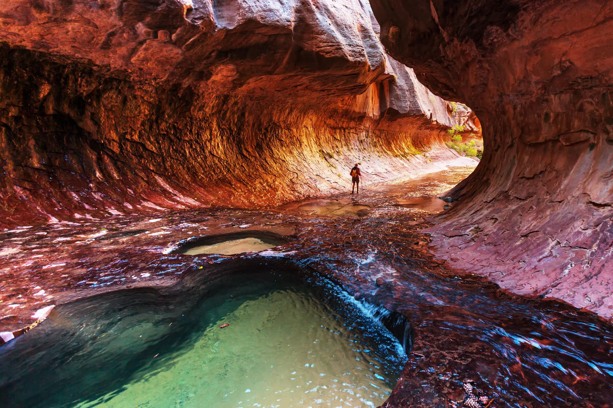A passage through a canyon with a curved overhang almost forming a tunnel