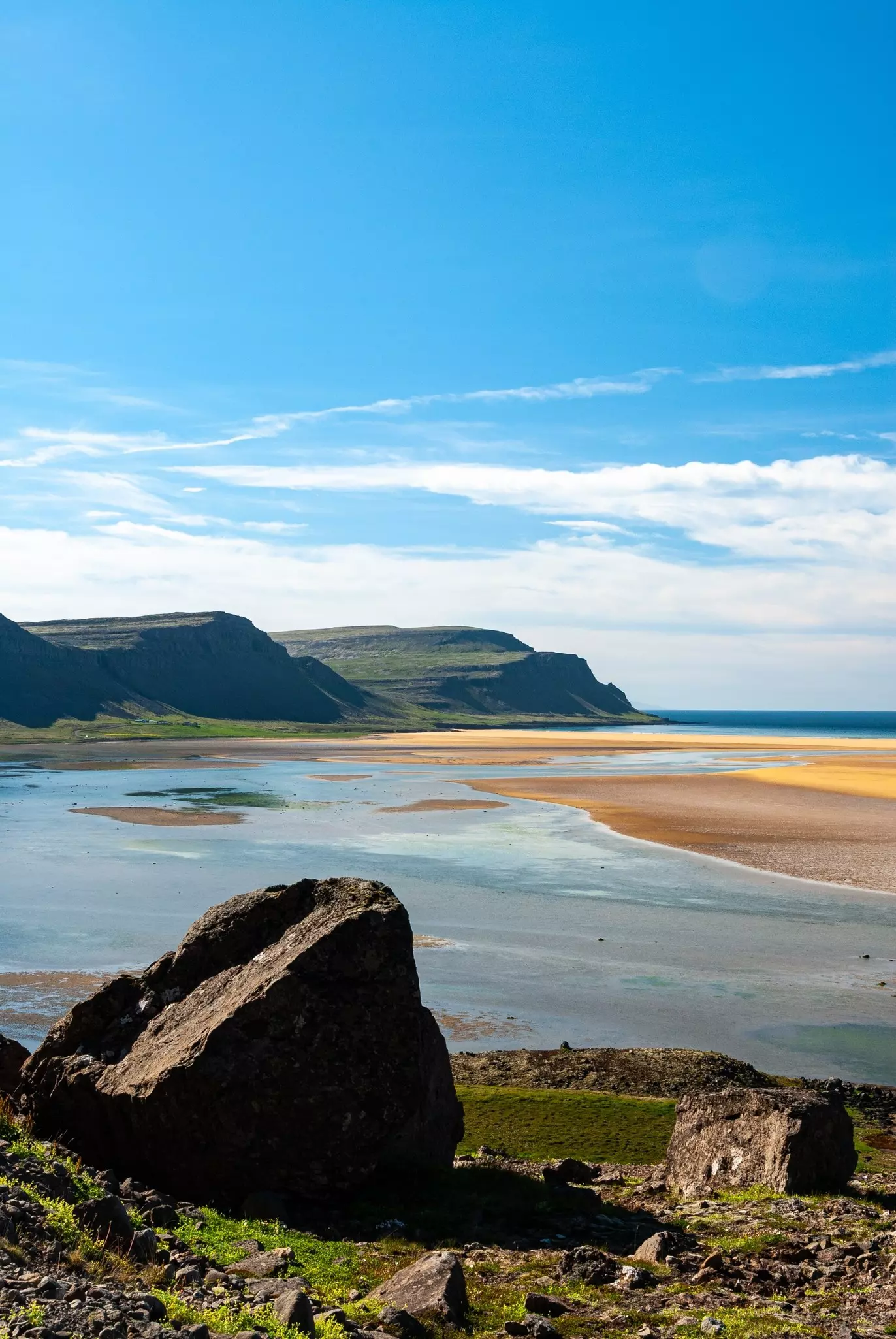 dramatic volcanic cliffs meet the ocean and red sand on a beach in Iceland