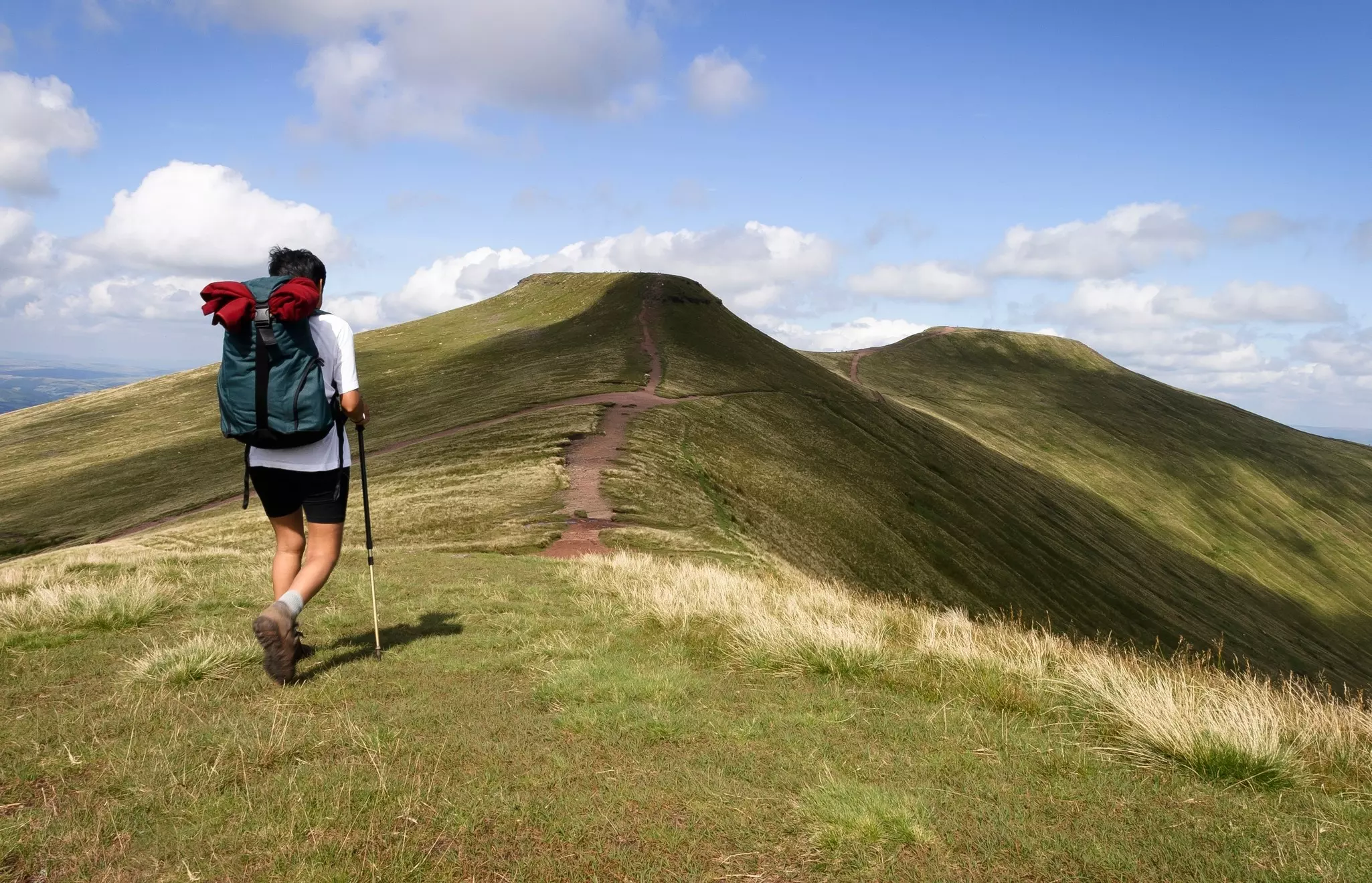 Woman hiking in Welsh hills towards Pen-y-Fan, Brecon Beacons.