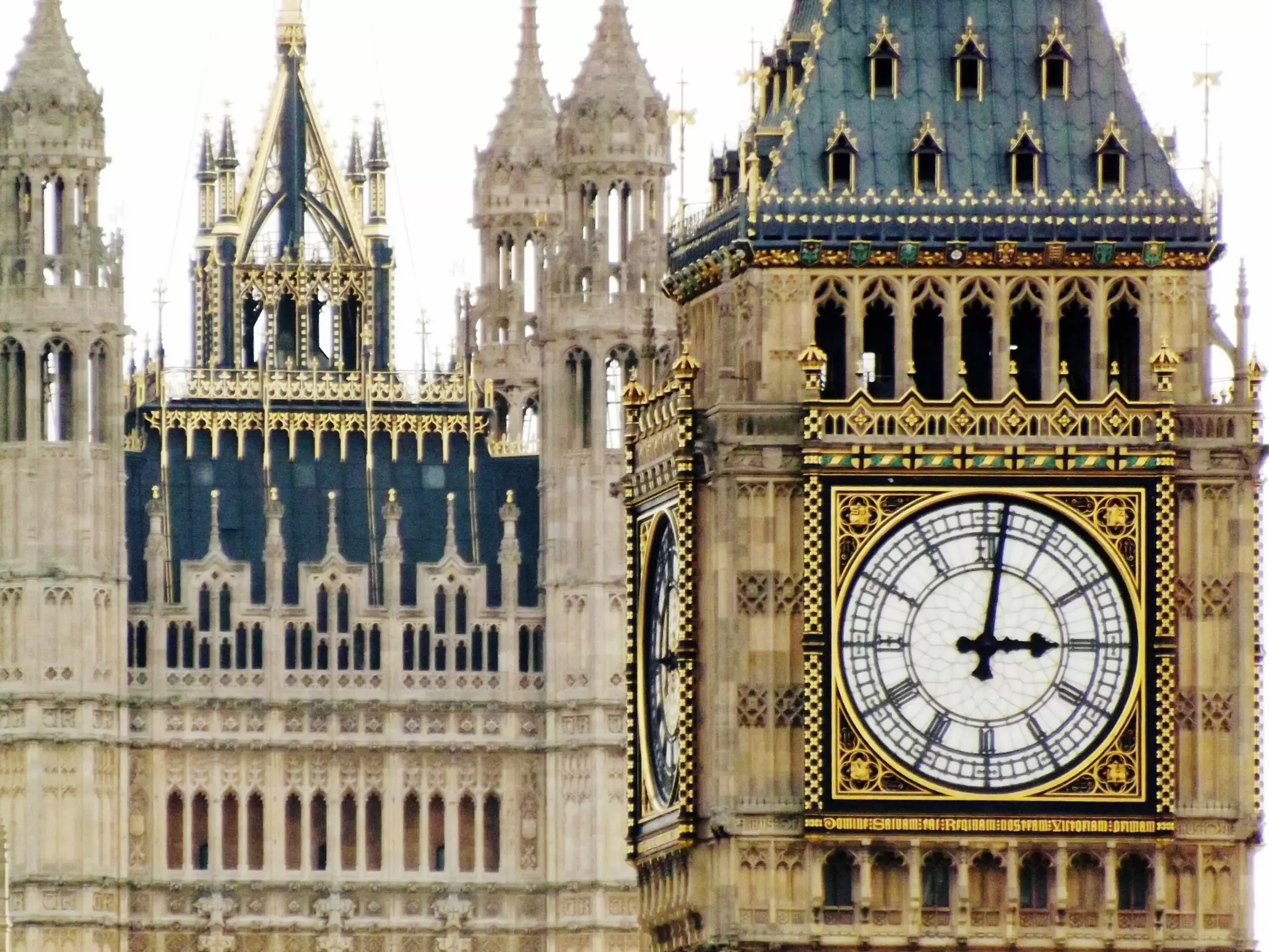 Close-up shot of a huge white clock face with black numbers in a Neo-Gothic tower