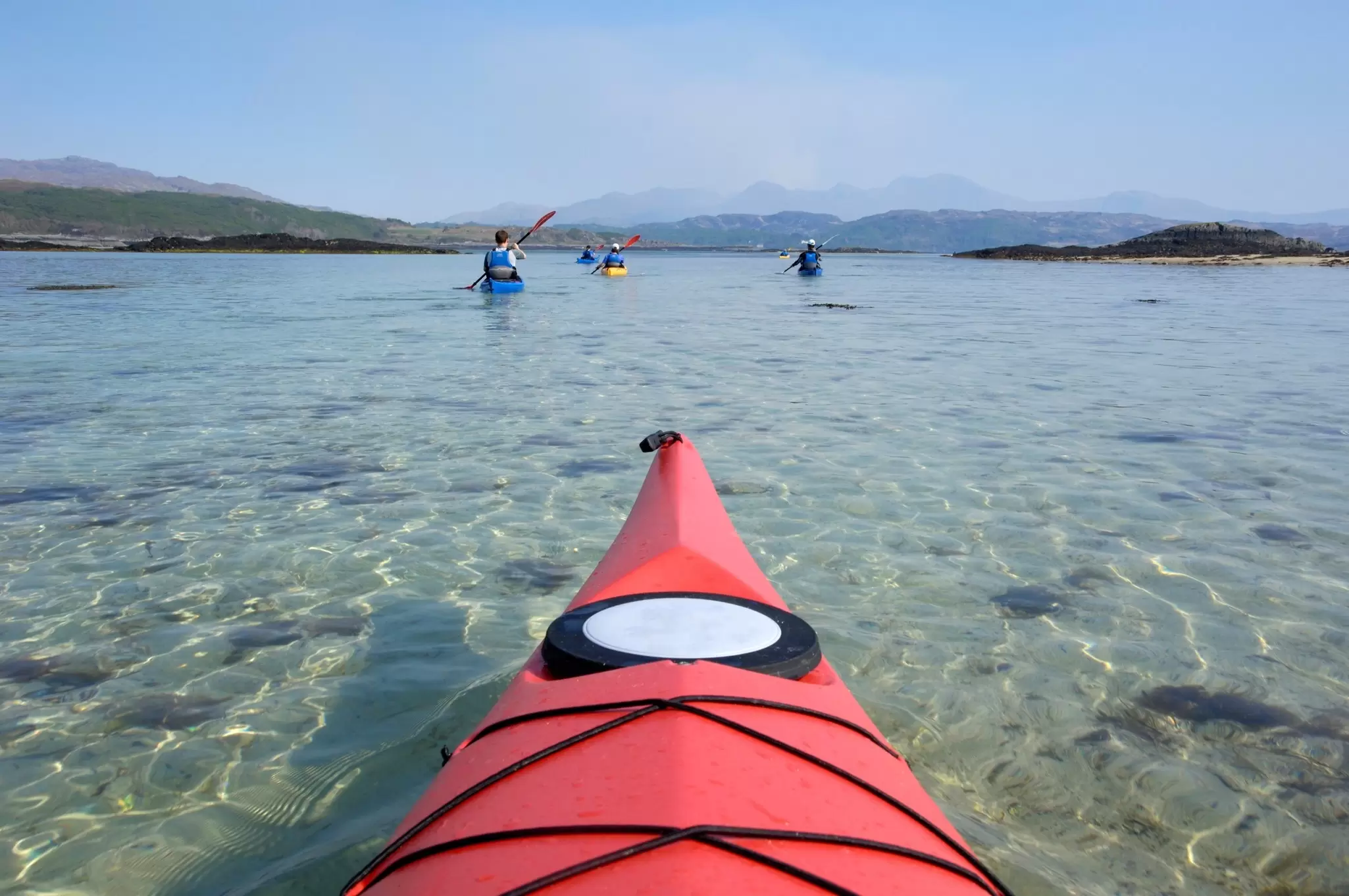 A group of people sea kayaking near Arisaig on the edge of the Scottish Highlands.