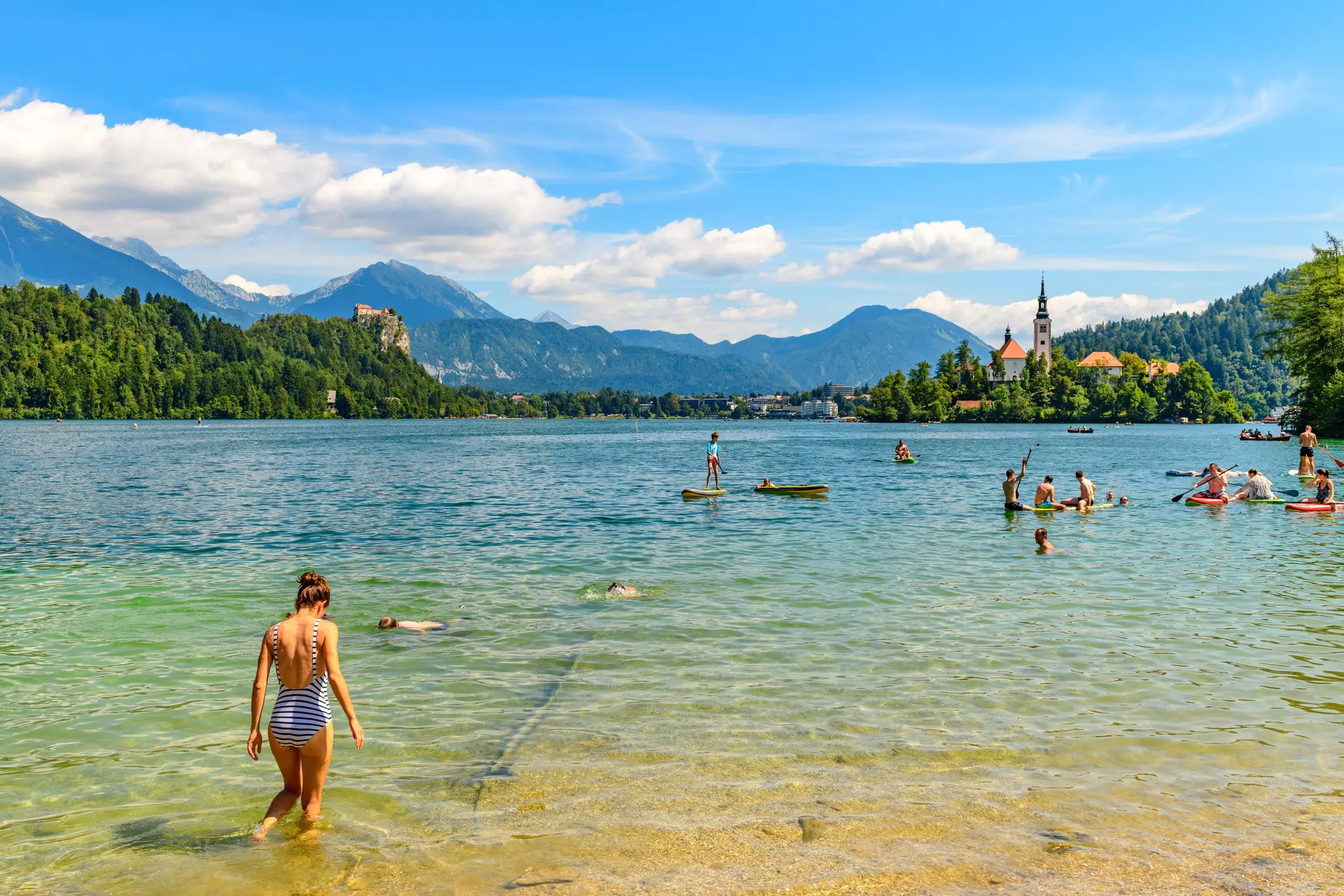 Swimming and bathing in Lake Bled on a background of a beautiful landscape with church on a small island - Slovenia symbol.