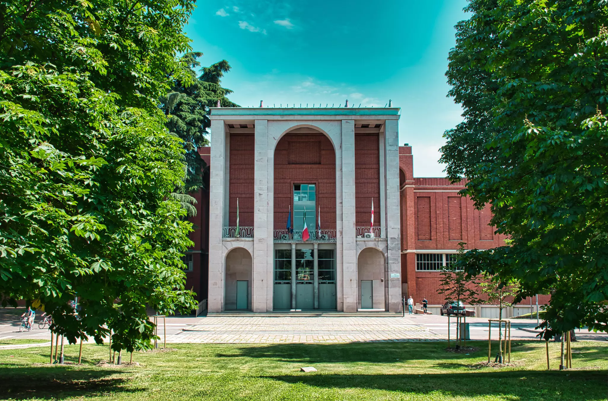 The entrance of Triennale di Milano on a sunny day with trees and grass in the foreground
