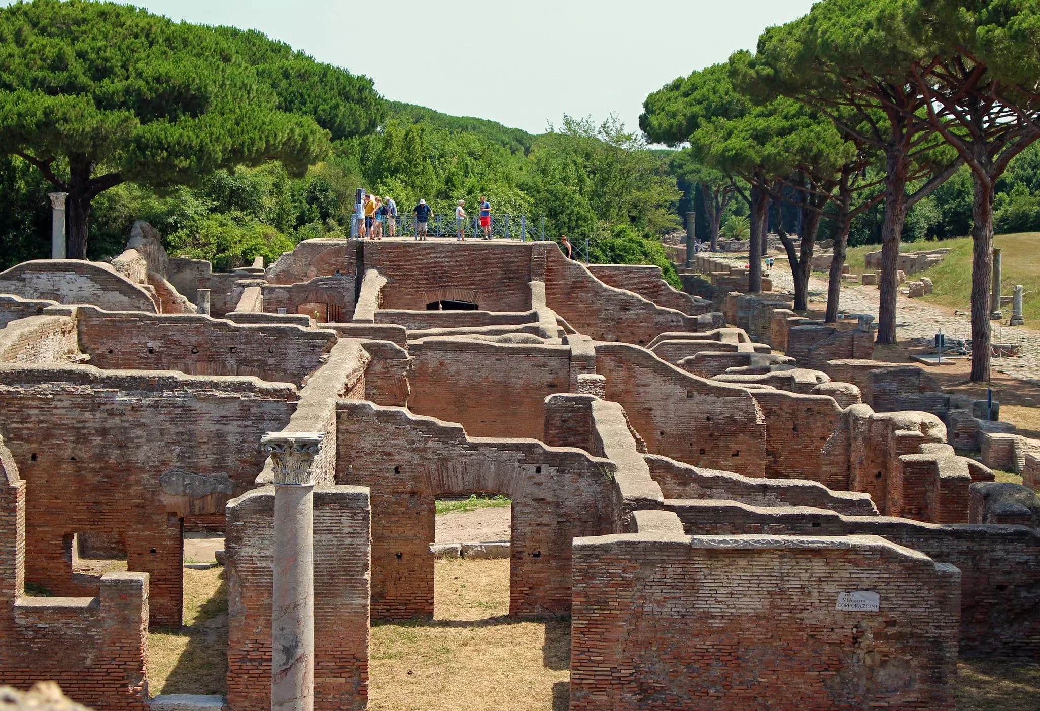 Tourists walk on a wall overlooking the Baths of Neptune to get a better view of the mosaic floors