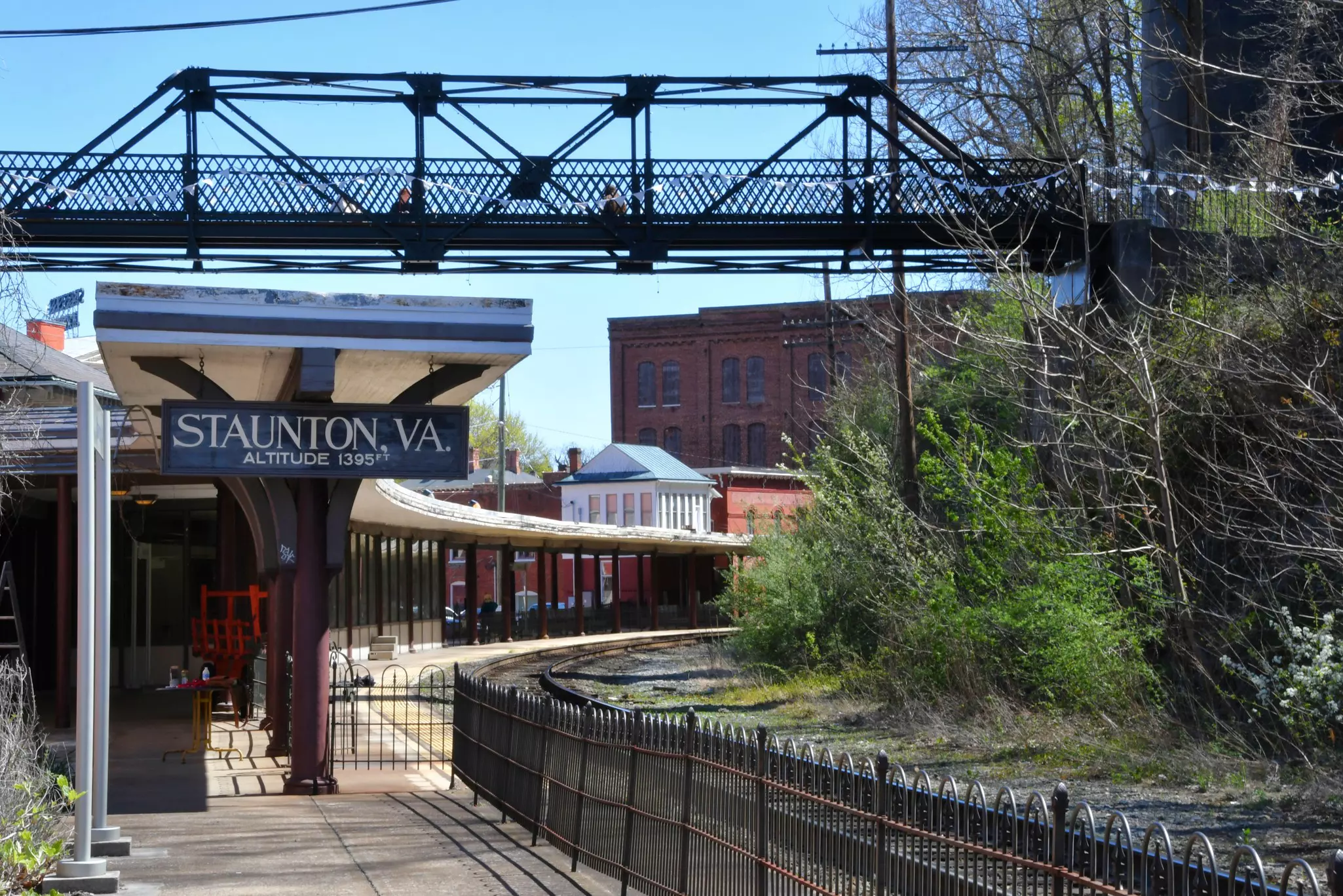 A single railroad track through a station with a long curved covered platform.